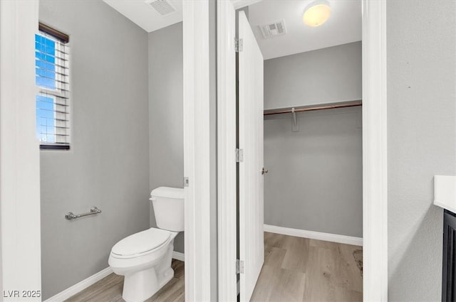 bathroom with toilet, visible vents, and wood finished floors