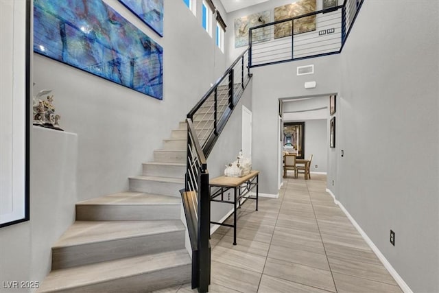 interior space with a high ceiling, visible vents, and baseboards