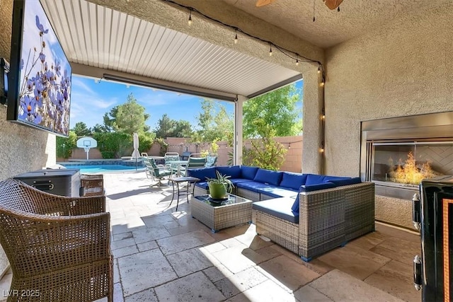 view of patio / terrace featuring a fenced in pool, a fenced backyard, ceiling fan, and an outdoor living space with a fireplace