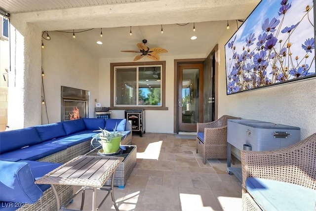 view of patio with an outdoor living space with a fireplace and a ceiling fan