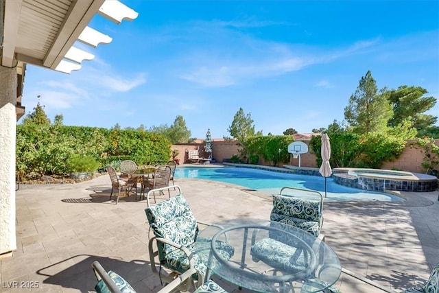 view of pool featuring a patio area, a fenced backyard, a pool with connected hot tub, and outdoor dining space