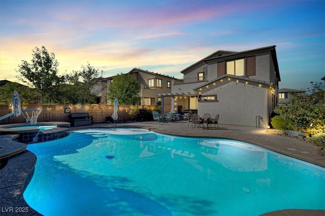 view of swimming pool with a pool with connected hot tub, fence, and a patio