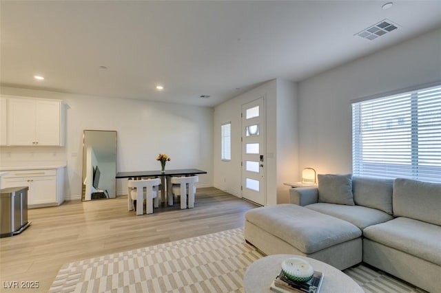 living room featuring light wood-type flooring, recessed lighting, visible vents, and a healthy amount of sunlight