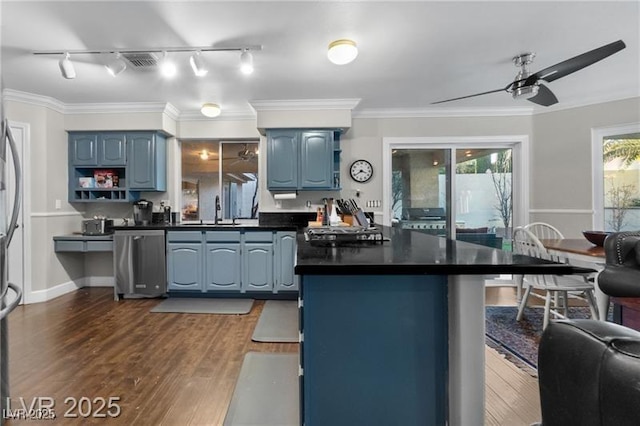 kitchen featuring dark wood-type flooring, blue cabinetry, dishwasher, dark countertops, and crown molding