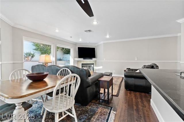 dining space with recessed lighting, dark wood-type flooring, visible vents, ornamental molding, and a glass covered fireplace