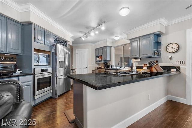 kitchen featuring stainless steel appliances, dark wood-type flooring, ornamental molding, and a peninsula