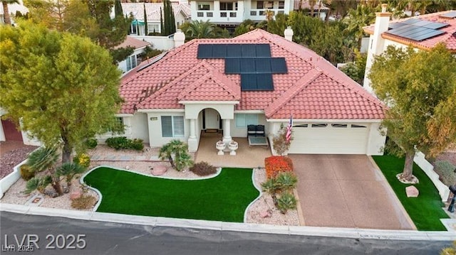 mediterranean / spanish-style home with stucco siding, solar panels, an attached garage, driveway, and a tiled roof