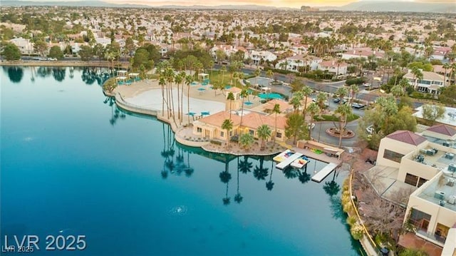 aerial view at dusk with a water view and a residential view