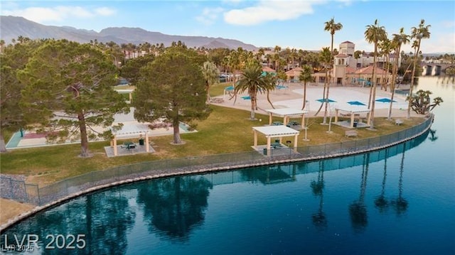 view of swimming pool with a lawn and a water and mountain view