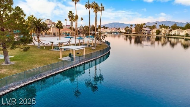 view of dock featuring a residential view, a yard, fence, and a water and mountain view