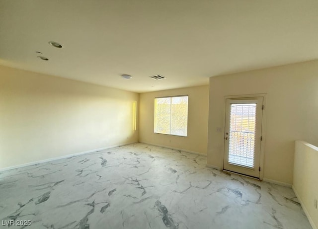 empty room with marble finish floor, visible vents, and baseboards