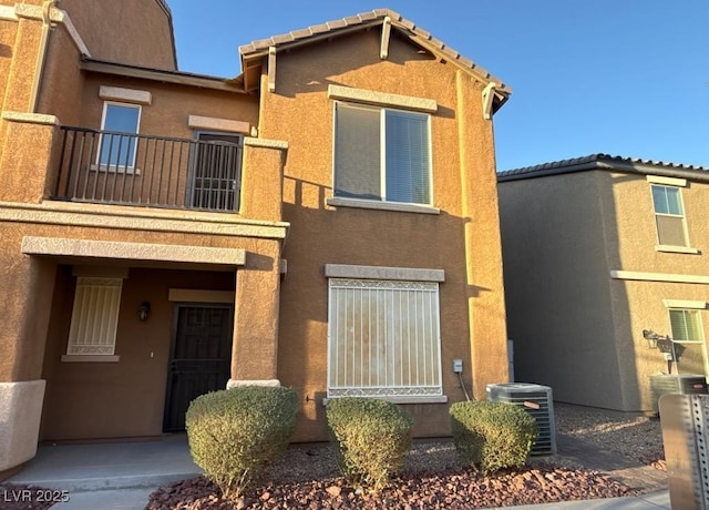 townhome / multi-family property featuring a tiled roof, cooling unit, and stucco siding