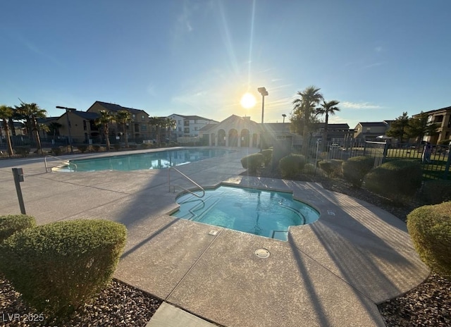 pool featuring fence, a hot tub, and a patio