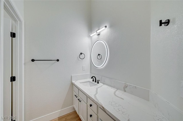 bathroom with wood finished floors, vanity, and baseboards