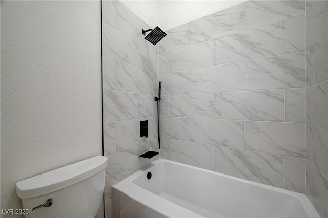 bathroom with toilet, tub / shower combination, and a textured wall