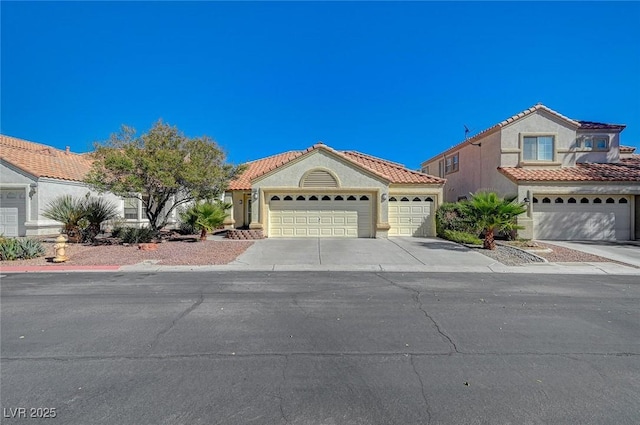 mediterranean / spanish home featuring concrete driveway, an attached garage, a tile roof, and stucco siding