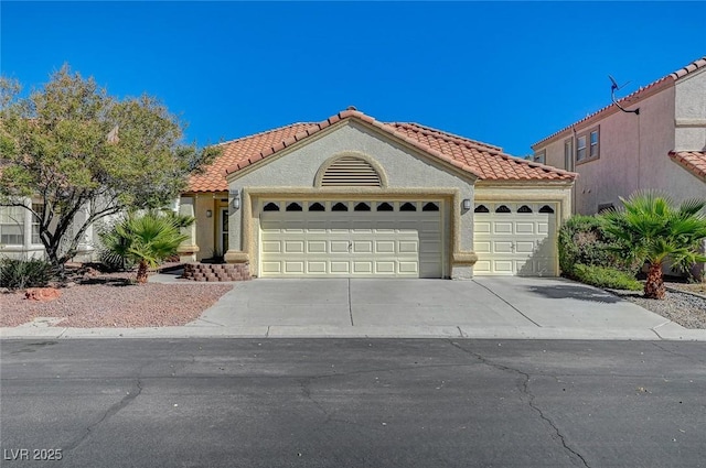 mediterranean / spanish house with a tile roof, driveway, an attached garage, and stucco siding