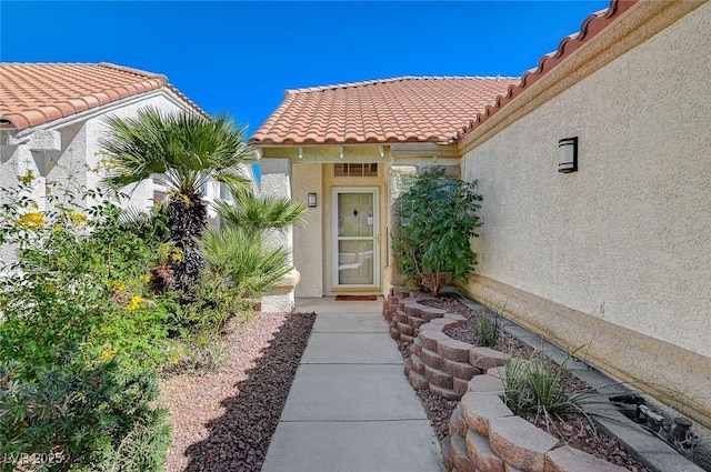 doorway to property with a tile roof and stucco siding