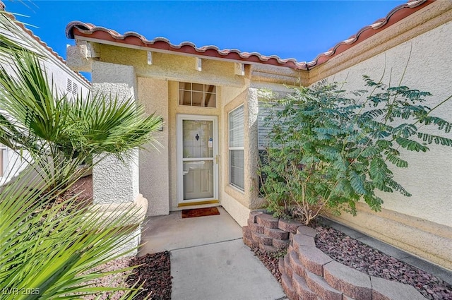 entrance to property featuring a tiled roof and stucco siding