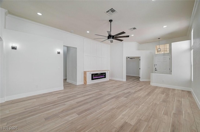 unfurnished living room with light wood-type flooring, a glass covered fireplace, visible vents, and ceiling fan