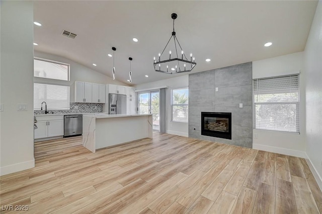 kitchen featuring a kitchen island, open floor plan, stainless steel appliances, a fireplace, and a sink