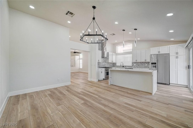 kitchen featuring visible vents, high quality appliances, vaulted ceiling, light wood-type flooring, and tasteful backsplash