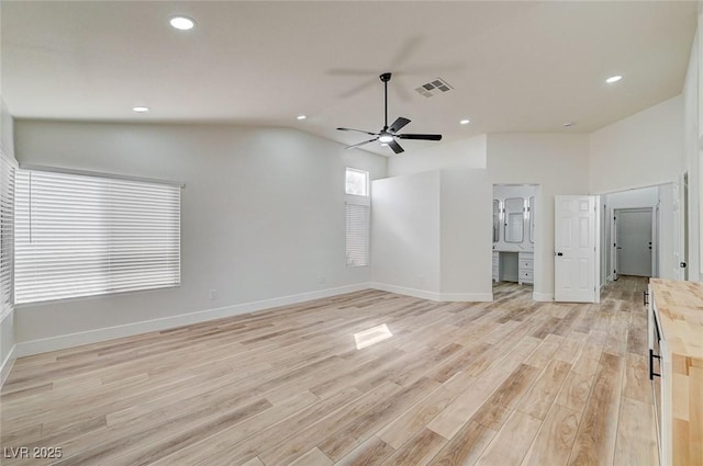 interior space featuring light wood-style flooring, visible vents, vaulted ceiling, and baseboards