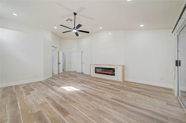 unfurnished living room featuring visible vents, a glass covered fireplace, light wood-style flooring, and baseboards