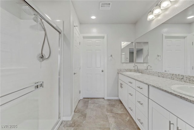 bathroom with double vanity, visible vents, a sink, a shower stall, and baseboards