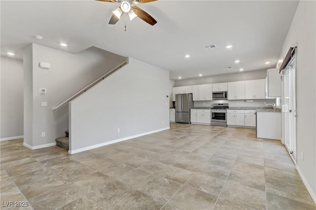 kitchen with a sink, visible vents, white cabinetry, open floor plan, and appliances with stainless steel finishes