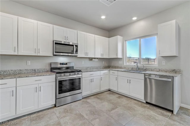 kitchen featuring light stone counters, stainless steel appliances, a sink, visible vents, and white cabinetry