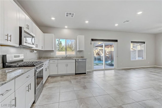 kitchen with light stone countertops, visible vents, stainless steel appliances, and a sink