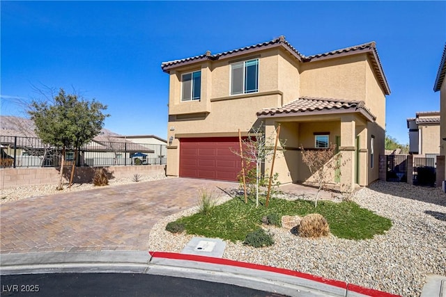 mediterranean / spanish home with decorative driveway, stucco siding, an attached garage, fence, and a tiled roof