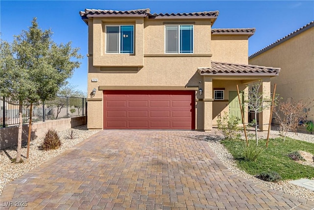 mediterranean / spanish-style house featuring a garage, a tile roof, fence, decorative driveway, and stucco siding