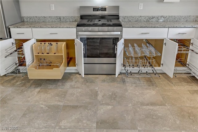 kitchen with light stone counters, stainless steel gas range, and white cabinets