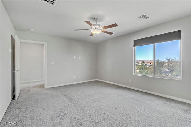 carpeted empty room with baseboards, visible vents, and ceiling fan