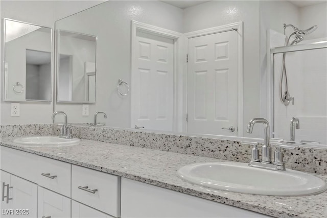 full bathroom featuring double vanity, a shower stall, and a sink