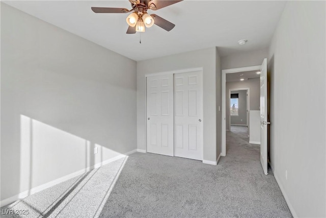 unfurnished bedroom with ceiling fan, a closet, baseboards, and carpet flooring