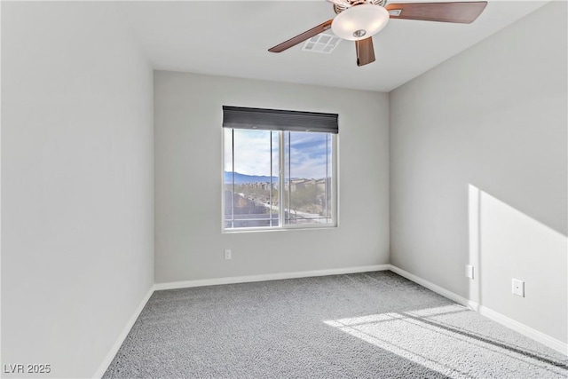 carpeted spare room featuring baseboards, visible vents, and ceiling fan