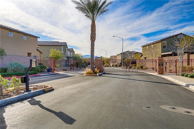 view of street featuring a gate, a residential view, a gated entry, and curbs