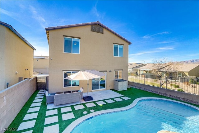 back of house with a fenced in pool, a patio, a fenced backyard, outdoor lounge area, and stucco siding