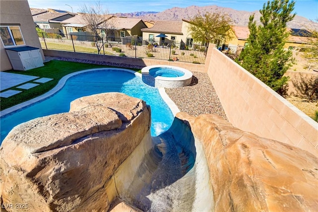 view of pool featuring a residential view, a pool with connected hot tub, a fenced backyard, and a mountain view