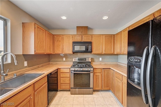 kitchen with light tile patterned floors, a sink, black appliances, light countertops, and tasteful backsplash