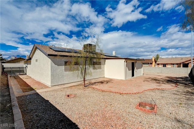 back of property featuring stucco siding, roof mounted solar panels, and fence private yard