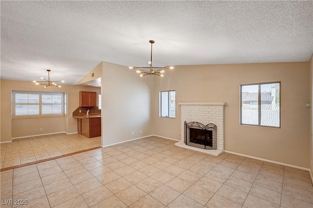 unfurnished living room with light tile patterned floors, a notable chandelier, a brick fireplace, and a healthy amount of sunlight