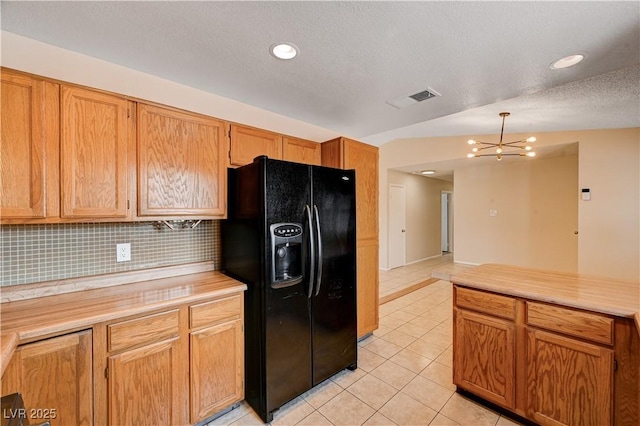 kitchen featuring visible vents, light countertops, black fridge, an inviting chandelier, and light tile patterned flooring