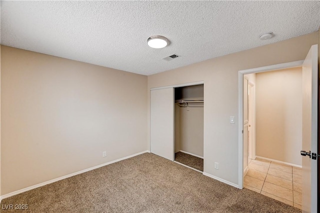 unfurnished bedroom featuring visible vents, a textured ceiling, a closet, carpet, and baseboards