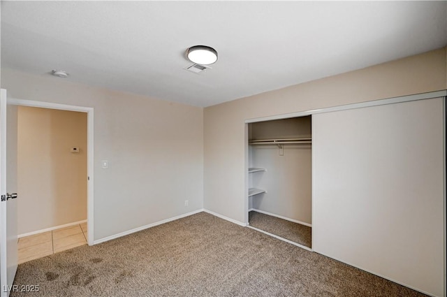 unfurnished bedroom featuring carpet flooring, baseboards, visible vents, and a closet