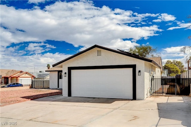 garage with concrete driveway, a gate, and fence