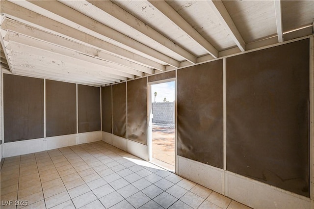 spare room featuring beam ceiling and light tile patterned floors